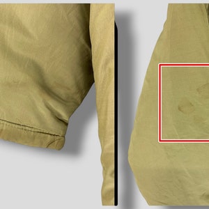 Puede incluir: Primer plano de una chaqueta caqui. La chaqueta tiene cierre de botones y un bolsillo. El pu&ntilde;o de la manga es visible. La tela presenta algunas manchas. La chaqueta parece estar hecha de un material ligero.