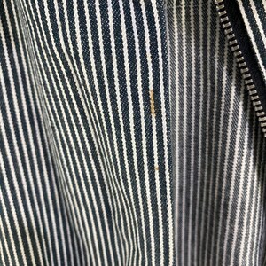 May include: Close-up of a black and white striped fabric with a zipper. The fabric is woven with thin black stripes and wider white stripes.