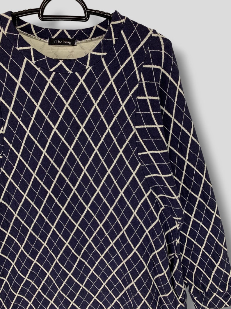 May include: Navy blue long-sleeve shirt with a white diamond pattern. The shirt has a crew neck and the text "Yf for living" is visible on the neckline.