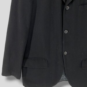 May include: A black blazer with a three-button closure and a single pocket on the left side.