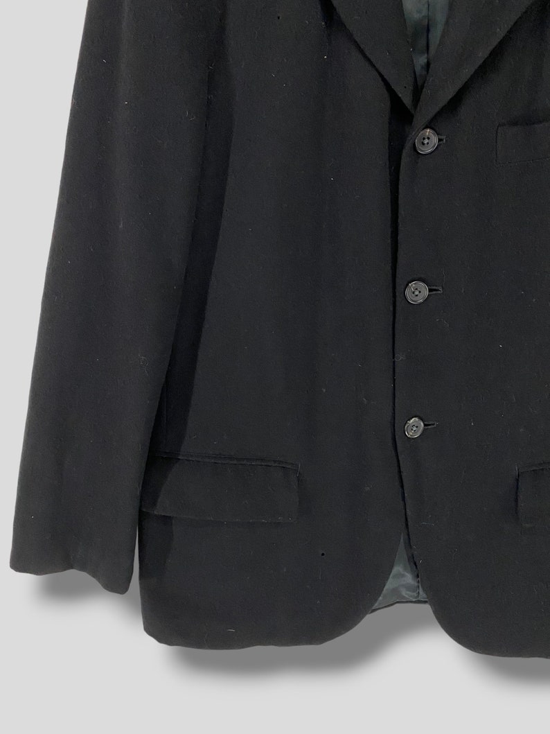 May include: A black blazer with a three-button closure and a single pocket on the left side.