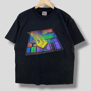 Op de afbeelding: Een zwart t-shirt met korte mouwen en een afbeelding van een kleurrijke computerprocessorchip op de voorkant. De afbeelding toont een geel vierkant met de tekst 'intel inside' en 'pentium' erop, tegen een veelkleurige printplaat.