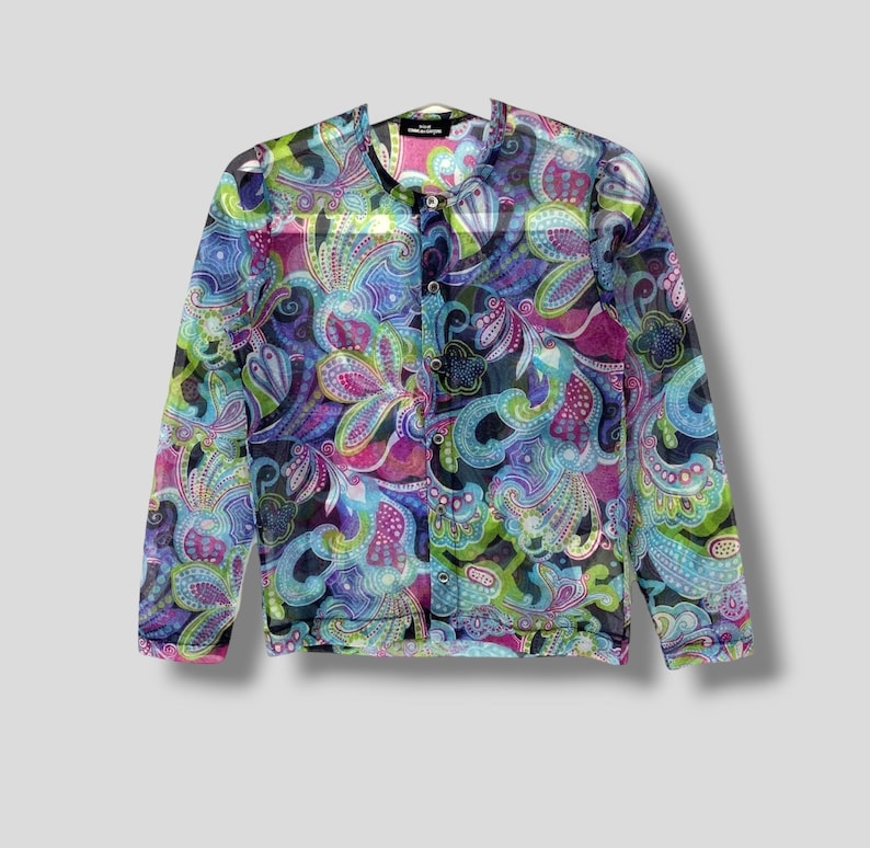 May include: A long-sleeved, sheer button-up shirt with a paisley print in shades of blue, green, pink, and purple.