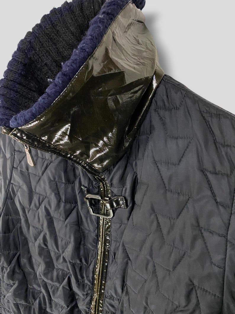 May include: A black quilted jacket with a black patent leather collar and a zipper closure. The jacket has a diamond-shaped quilted pattern.