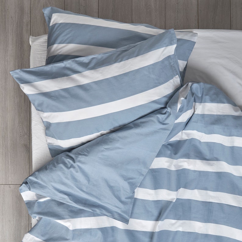 Puede incluir: Un juego de cama a rayas azul y blanco con una funda n&oacute;rdica y dos fundas de almohada.