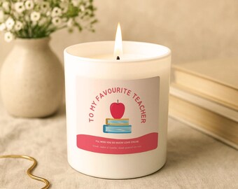 Op de afbeelding: Een witte kaars in een glazen pot met een brandende lont. Het etiket bevat de tekst TO MY FAVOURITE TEACHER, een illustratie van een rode appel op twee boeken, en de tekst I'LL MISS YOU SO MUCH! LOVE CHLOE en Scent: Amber & Vanilla Hand-poured soy wax.