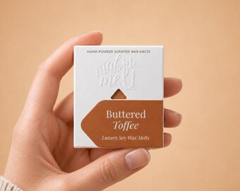 May include: A square white box of hand-poured scented wax melts. The packaging features the text "mah me melt" embossed at the top and a brown label with the white text "Buttered Toffee" and "Luxury Soy Wax Melts" printed on the front.