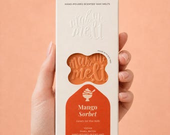 May include: A rectangular white cardboard box containing Mango Sorbet scented wax melts. The packaging features the text "make me melt" in embossed lettering, a cutout window revealing the orange wax, and a graphic of a dessert bowl.