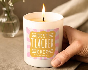 Op de afbeelding: Een witte kaars in een glazen pot met een brandende lont. Het etiket heeft een gele geschulpte rechthoek op een roze en wit gestreepte achtergrond met de tekst BEST TEACHER EVER en Mrs Tilly, You are the best! Love Ropers.