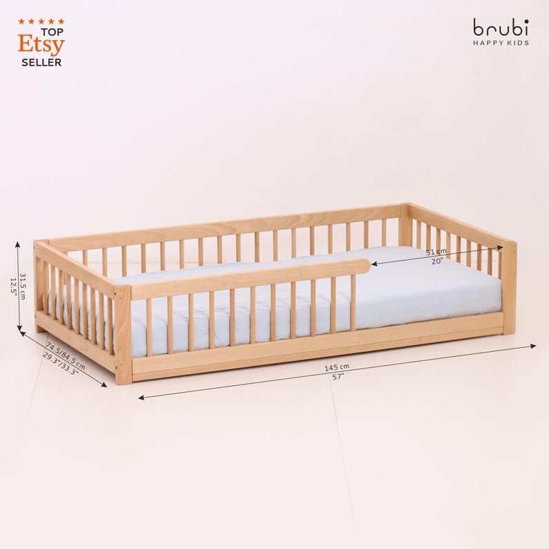 May include: A light-colored wooden toddler bed with a light blue mattress. The bed frame has a slatted design on the sides and headboard. The bed is 57 inches long, 20 inches wide, and 12.5 inches high. The Etsy seller logo is in the top left corner.