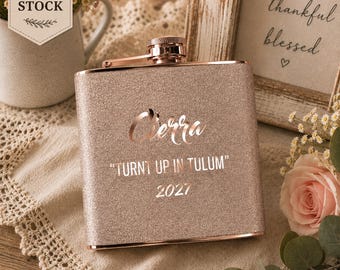Może przedstawiać: Metalowa piersiówka z wykończeniem z różowego złota z brokatem, wygrawerowana imieniem Cierra, napisem "TURNT UP IN TULUM" oraz rokiem 2027. Piersiówka posiada zakrętkę i prostokątny kształt z metalicznym połyskiem na swojej teksturowanej powierzchni.