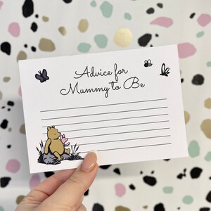 May include: A white card with black text that reads "Advice for Mummy to Be". There is a small illustration of Winnie the Pooh sitting on a rock with a pink flower. There are also small illustrations of butterflies and bees.