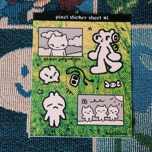 Peut inclure: Une planche d'autocollants pixel avec le texte "pixel sticker sheet #1". Elle présente des illustrations de personnages d'ours en noir et blanc sur un fond vert et jaune, avec l'inscription "do not forgive you".