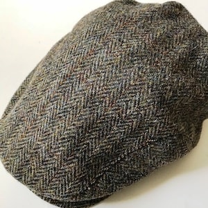 Puede incluir: Una gorra plana de tweed marrón y verde con un patrón de espiga.