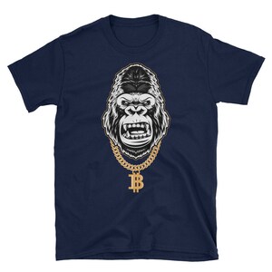 May include: A navy blue t-shirt featuring a black and white illustration of a gorilla wearing a gold chain with a bitcoin pendant.