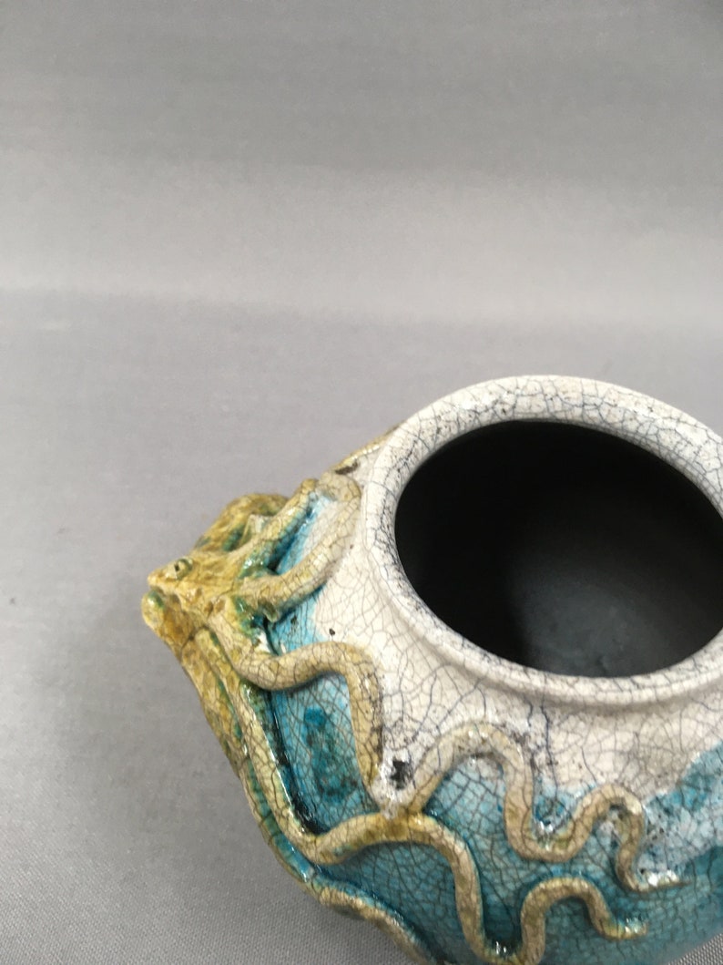 Octopus crawling around a pot vase