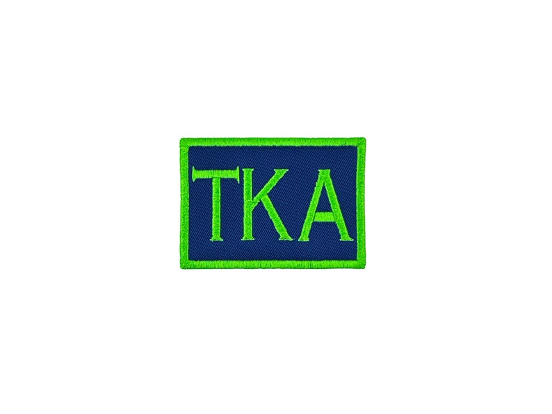 May include: A green and blue embroidered patch with the letters "TKA" in white.