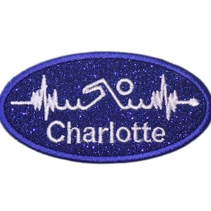 May include: Blue oval-shaped iron-on patch with white glitter and a white embroidered heartbeat with the name "Charlotte" underneath.