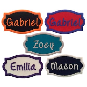 May include: Five colorful fabric name tags with embroidered names. The names are Gabriel, Zoey, Emillia, Mason, and Gabriel. The tags are in orange, blue, teal, purple, and red.