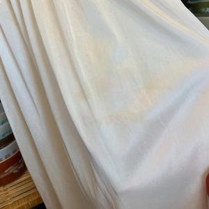 May include: A white slip with a gathered elastic waistband. The slip is made of a soft, silky fabric.