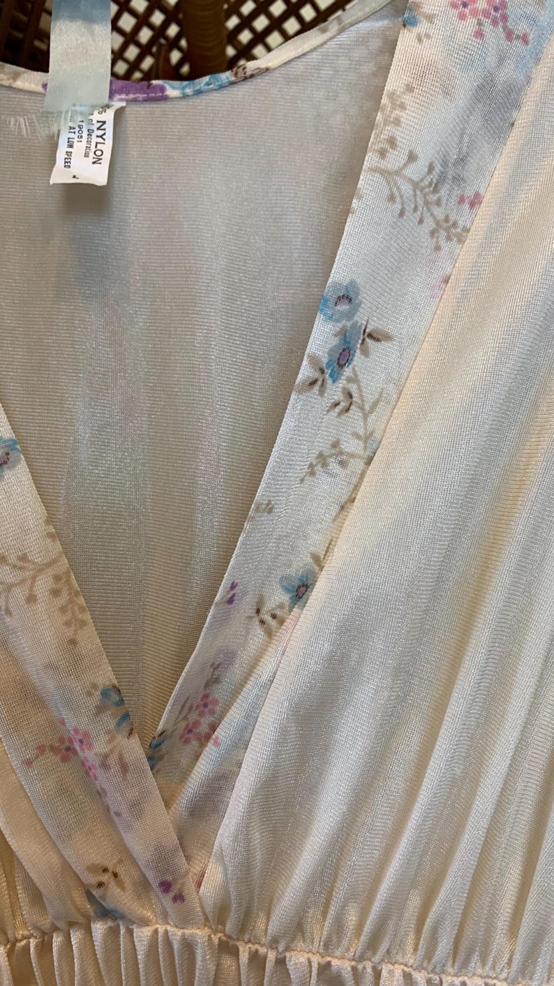 May include: A white, sheer, floral-patterned nightgown with a V-neckline. The fabric is made of 100% nylon and is machine washable at low speed.