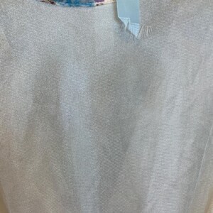 May include: A white sheer top with a blue and purple tie-dye pattern around the neckline.