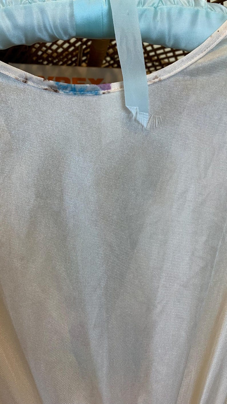 May include: A white sheer top with a blue and purple tie-dye pattern around the neckline.