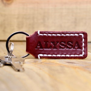 Burgundy leather keychain with white thread and silver keyring. Personalized with "ALYSSA"