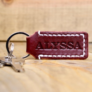 Burgundy leather keychain with white thread and silver keyring. Personalized with "ALYSSA"