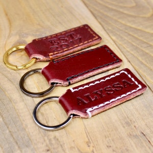 Burgundy leather keychain with brown thread and gold keyring. Personalized with "EST. 2017"
Burgundy leather keychain with white thread and silver keyring. Personalized with "ALYSSA"