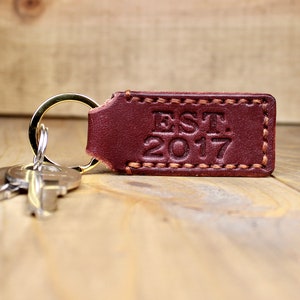 Burgundy leather keychain with brown thread and gold keyring. Personalized with "EST. 2017"