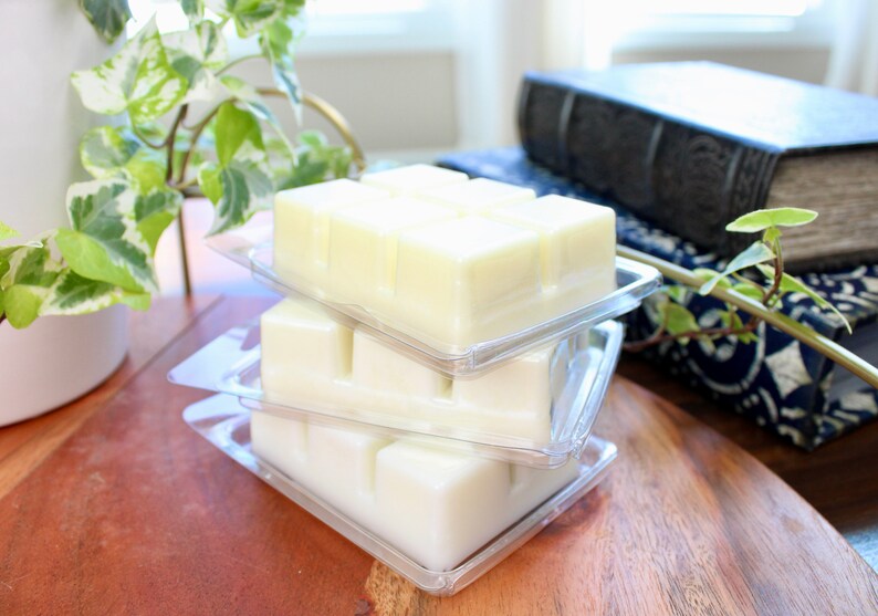 May include: Three clear plastic containers stacked on top of each other, each containing a white wax melt. The wax melts are divided into squares.