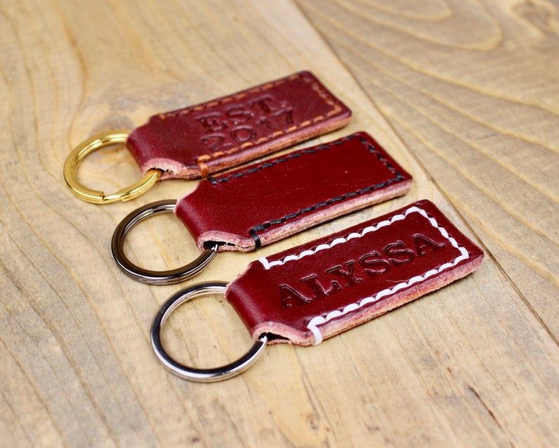 Burgundy leather keychain with brown thread and gold keyring. Personalized with "EST. 2017"
Burgundy leather keychain with white thread and silver keyring. Personalized with "ALYSSA"