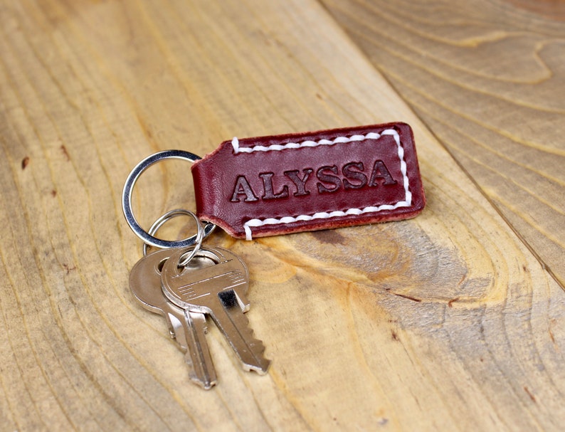 Burgundy leather keychain with white thread and silver keyring. Personalized with "ALYSSA"