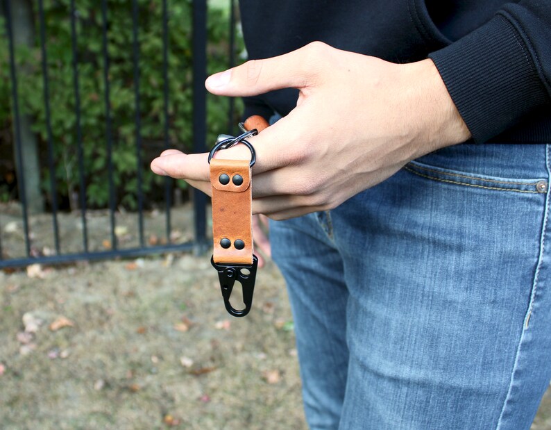 May include: A brown leather key chain with a black metal clip and two black rivets.