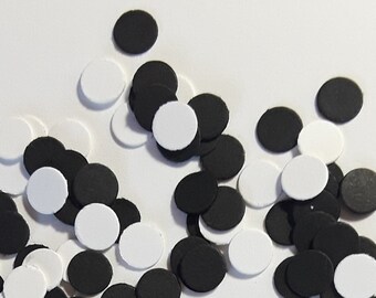 May include: A collection of black and white paper circles scattered on a white background. The circles are of various sizes and are arranged in a random pattern.