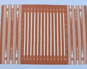 Könnte beinhalten: Ein rostfarbener Teppich mit einem weißen geometrischen Muster. Das Muster zeigt vertikale Linien und abstrakte Formen.