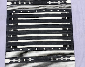Könnte beinhalten: Schwarz-weißer Teppich mit geometrischem Muster. Der Teppich hat einen Fransenrand.