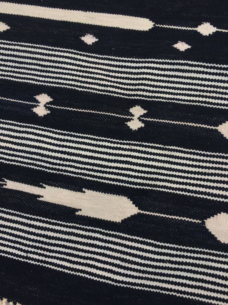 May include: Black and white striped fabric with a geometric pattern. The pattern is made up of thin white lines and thicker white lines that create a diamond shape.