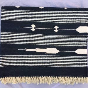 May include: Black and white striped rug with a geometric pattern. The rug has a fringe border.