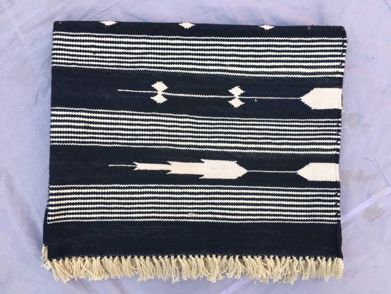 May include: Black and white striped rug with a geometric pattern. The rug has a fringe border.