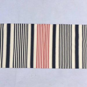 May include: A striped runner rug with black, white and red stripes. The rug has a fringe on both ends.