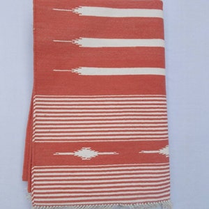 May include: A red and white striped throw blanket with a fringe border. The blanket has a geometric pattern in the center.