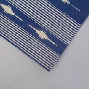 Peut inclure: Un tapis ray&eacute; bleu et blanc avec un motif g&eacute;om&eacute;trique. Le tapis est en coton et est parfait pour ajouter une touche de style &agrave; n'importe quelle pi&egrave;ce.