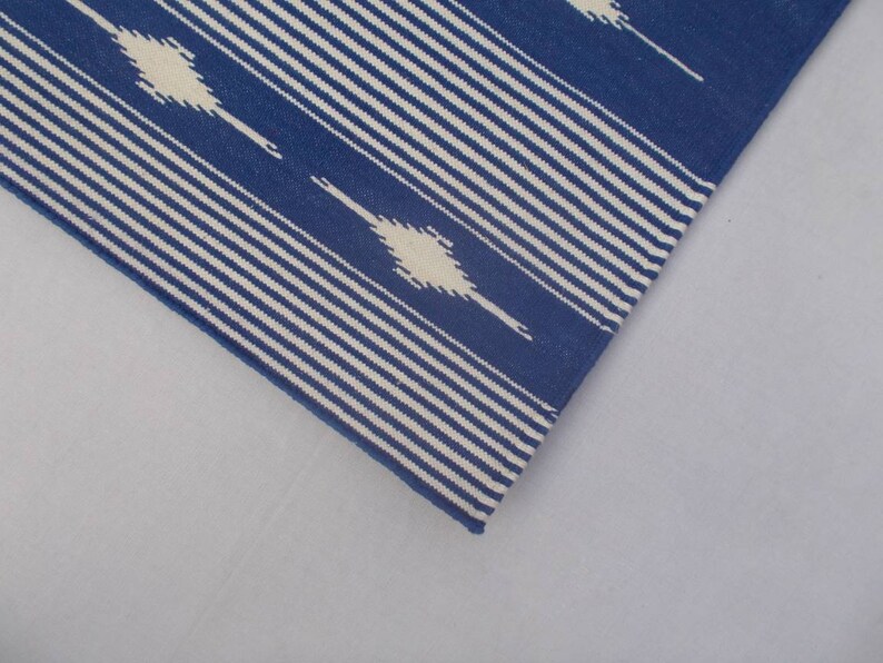 Peut inclure: Un tapis ray&eacute; bleu et blanc avec un motif g&eacute;om&eacute;trique. Le tapis est en coton et est parfait pour ajouter une touche de style &agrave; n'importe quelle pi&egrave;ce.