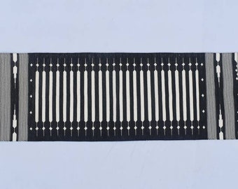 May include: Black and white striped runner rug with a geometric pattern. The rug has a fringe on both ends.