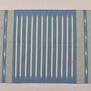 May include: A rectangular blue rug with vertical cream-colored stripes and fringed edges. The rug features a repeating pattern of cream-colored diamond shapes along the sides. The rug is suitable for indoor use.