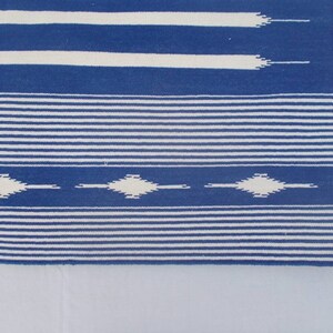 Peut inclure: Tapis ray&eacute; bleu et blanc avec un motif en losange. Le tapis a une texture tiss&eacute;e et une bordure frang&eacute;e.