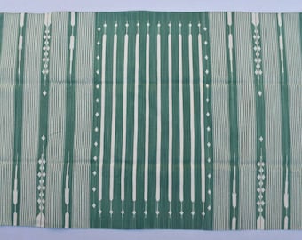 May include: A green and white striped rug with a geometric pattern. The rug has a fringed border.