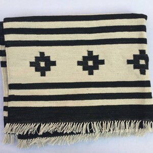 May include: Black and white striped throw blanket with a fringe border and three black geometric designs.